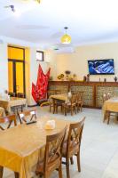 een restaurant met tafels en stoelen en een flatscreen-tv bij ELANI Hotel in Samarkand