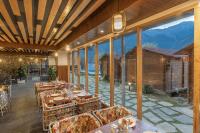 een restaurant met tafels en stoelen en grote ramen bij Echor Himalayan Heights Manali in Manāli