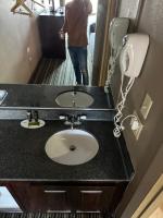 eine Person, die vor einem Waschbecken in einem Badezimmer steht in der Unterkunft labh inc Motel in Norfolk