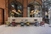 ein Restaurant mit bunten Stühlen, einem Tisch und Kronleuchtern in der Unterkunft Cassia Rama 9 Bangkok, part of Banyan Group in Bangkok