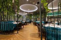 ヒサリャにあるEmpire Balneo & Spa Hotelの青いテーブルと椅子、植物のあるレストラン