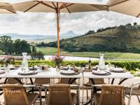 Una mesa con sillas y una sombrilla en un patio. en Oaklands Farm Stay, en Van Reenen