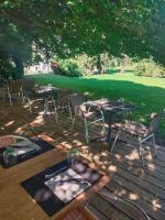 Un patio con mesas y sillas en una terraza de madera. en Hôtel Bon Repos, en Barbezieux