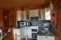 a small kitchen with white cabinets and a sink at East Crinnis Log Cabin in Par