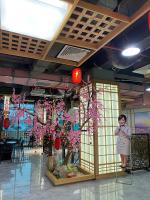 Una mujer de pie junto a un árbol con flores rosas en Infinity Hotel, en Thái Bình
