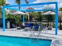 una piscina con sillas, mesas y sombrillas en Tru By Hilton Miramar, en Miramar