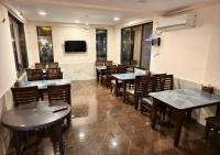 un restaurant avec des tables, des chaises et une télévision dans l'établissement Ashokleela Resort, à Alībāg