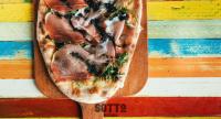 a pizza on a wooden cutting board on a table at Sliema Tigne Suites in Sliema