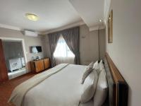 a bedroom with a large white bed with pillows at Ngwenya Hotel &amp; Conference Centre in Klerksdorp