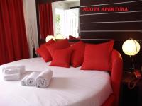 Una cama con almohadas rojas y toallas. en Hotel Paradise Airport, en Forlì