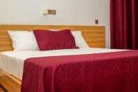 Una cama con una manta roja encima. en Hôtel ZUMAH, en Ouagadougou