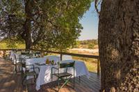 Una mesa con mesas y sillas blancas sobre una terraza de madera. en Inyati Game Lodge, en Reserva de caza Sabi Sand