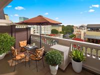 a balcony with a table and chairs and an umbrella at Hotel de l'Opera Hanoi - MGallery in Hanoi