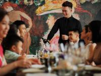 a man standing in front of a group of people at a table at Hotel de l'Opera Hanoi - MGallery in Hanoi
