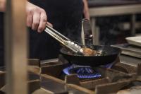 una persona cocinando comida en una sartén en una estufa en Crazy Bear Stadhampton, en Stadhampton