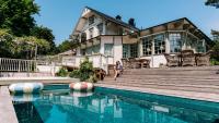 una mujer sentada frente a una casa con piscina en Villa Strandvägen, en Ystad