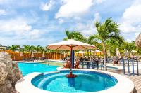 a pool with an umbrella and a table and chairs at The Ritz Village in Willemstad