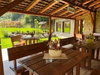 een terras met houten tafels en banken en een tuin bij Pietrele Doamnei in Pojorâta