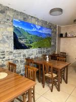 een eetkamer met houten tafels en een tv aan een stenen muur bij Casa tra i boschi in Esino Lario