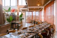 un restaurante con mesas largas, sillas y ventanas en Tĩnh Lạc Viên Homestay Bảo lộc, en Bao Loc