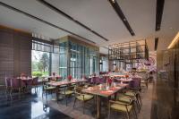 um restaurante com mesas e cadeiras em uma sala em Crowne Plaza Harbin Songbei by IHG em Harbin