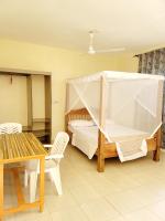 Un dormitorio con una cama y una mesa y sillas. en Casuarina Lounge, en Malindi