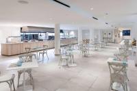a restaurant with white tables and chairs and a counter at Sol Fuerteventura Jandia - All Suites in Morro del Jable