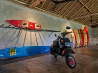 uno scooter parcheggiato in una stanza con tavole da surf sul muro di Gili Dua Resort a Sekongkang