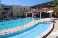 a large swimming pool with chairs and a building at Zorbas studio deluxe in Moraitika