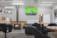 Una habitación con mesas y sillas y un televisor en la pared. en Canberra Holiday Village, en Canberra