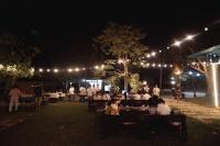 een groep mensen die 's nachts aan tafel in een park zitten bij Amphawa Horse Farm Resort in Ban Bang Khan Taek (1)