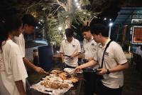 een groep mannen die rond een grill staan met vlees bij Amphawa Horse Farm Resort in Ban Bang Khan Taek (1)