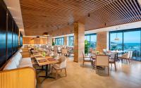 a restaurant with tables and chairs and windows at Radisson Resort Mui Ne in Mui Ne