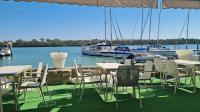 a group of tables and chairs with boats in the water at Casa Flotante El Refugio del Pirata in El Puerto de Santa María