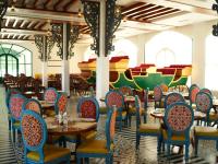 a dining room with tables and chairs and a mural at Resort Titli in Shānti Niketan