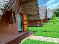 a building with a wooden door and a grass yard at Soanala in Moramanga