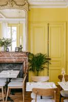 ein Restaurant mit gelben Wänden und Tischen und einem Spiegel in der Unterkunft Le Charmant Hôtel in Saint-Ouen