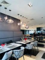 Un comedor con mesas, sillas y luces. en MADR Excellence at Novotel Manila Hotel Residence Acqua, en Manila