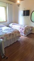two beds in a room with a tv on the wall at Pousada Sino dos Ventos in Campos do Jordão