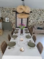 einen Esstisch mit einem weißen Tischtuch und Stühlen in der Unterkunft Home Emoi in La Gouesnière