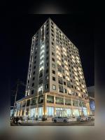 Un edificio alto con coches aparcados delante. en MyFlower 3 Hotel, en Erbil