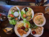 un grupo de platos de comida en una mesa de madera en Loom Cafe Banrai ลูมคาเฟ่บ้านไร่, en Ban Sanam