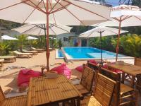 a patio with tables and umbrellas next to a pool at Leelawadee Bungalow and Restaurant in Mae Nam