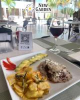 um prato de comida e um copo de vinho numa mesa em New Garden Hotel em Sosúa