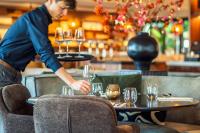 a man setting up glasses on a table in a restaurant at Eilandhotel Texel - Nieuw geopend hotel in De Cocksdorp