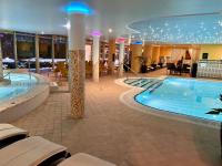 a large pool in a hotel with tables and chairs at Calimbra Wellness Hotel Superior in Miskolctapolca