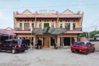 Dos coches estacionados en un estacionamiento frente a un edificio. en RedDoorz at Hotel Grand Yuda Tenggarong, en Samarinda