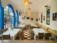 a restaurant with tables and chairs and a couch at Qodwa Palace Riad & SPA in Fourou
