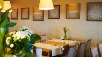 a dining room with tables and flowers on the wall at Hotel Antek in Zlinice
