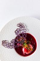 Un plato blanco con un tazón de comida con uvas. en Plume Suites, en Fleurey-sur-Ouche